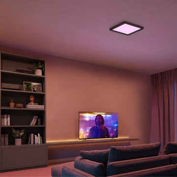 Musta, neliön muotoinen kattovalaisin luo violettia valoa olohuoneeseen, jossa on TV